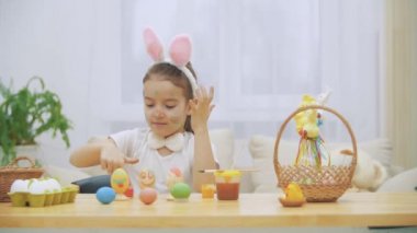 Litlte oynak kız, tavşan kulakları kafasında giyen elleri boyuyor. Aniden, biri onu fark ettim. O korkmuş ve ellerini sakladım.