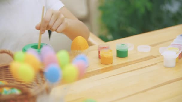 Креативний хлопчик малює пасхальне яйце жовтого кольору за допомогою пензлика . — стокове відео