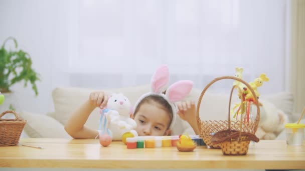 Piccola ragazza carina e adorabile sorride e gioca con polli colorati uova e conigli. Bunny mangia il suo cibo preferito: l'uovo di Pasqua. Concetto vacanza di Pasqua . — Video Stock