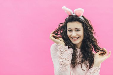 Genç güzel kız ayakta karşı bir pembe. Tavşan kulakları kafasına. Bu süre içinde tutan saç ayrılmaktadır. İçtenlikle gülümsüyor. Paskalya.