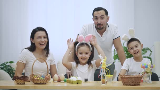 Famille heureuse et joyeuse : mère, père et deux enfants sourient beaucoup et partagent leurs émotions positives sur fond blanc. Concept de Pâques . — Video