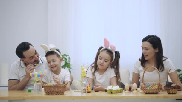 Familia feliz y alegre: madre, padre y dos niños sonríen ampliamente y comparten sus emociones positivas en el fondo blanco. Concepto Pascua . — Vídeo de stock