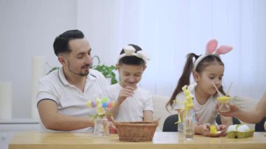 Çocuklarıyla birlikte babasıdır: kızı ve oğlu, tavşan kulakları, Paskalya süsleri ile tatil masada oturan giyiyorsun. Anne veren araçlar tekne bir ailenin her üyesi için hazırlanıyor.