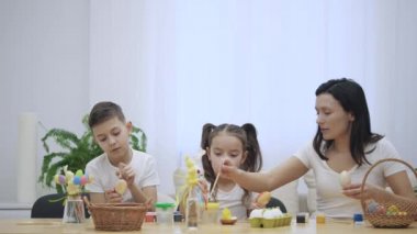 Çocuklarıyla birlikte annedir: kızı ve oğlu, Paskalya süsleri ile tatil masada oturan. Paskalya yumurtaları renklendirme konsantre ve yapımı craft, ailedir. Aniden, baba gelir ve