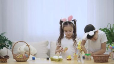 Neşeli ve eğlenceli kardeşleri ve renklendirme Paskalya yumurtaları. Küçük kız bir fikir geldi.