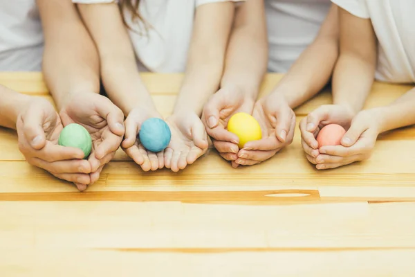 Vier bunte Ostereier in den Händen von Mutter, Vater, Schwester und Brüdern wie in den Nestern. verschwommener Hintergrund. — Stockfoto