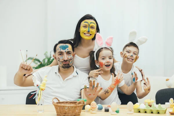 Kreative Familie, Kinder in Hasenohren. alle mit farbigen Gesichtern. sie sind extrem glücklich und zeigen es der Kamera, lächeln und posieren komisch. — Stockfoto