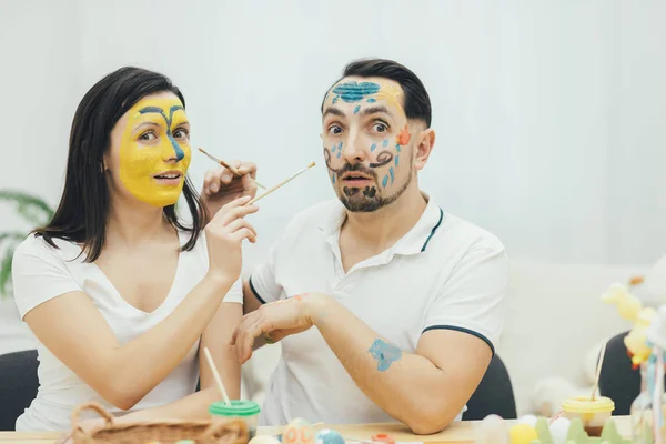 A mãe e o pai pintaram os rostos em vez de ovos de Páscoa. Comportamento tolo. Emoções imperdoáveis. Tinta e cor . — Fotografia de Stock