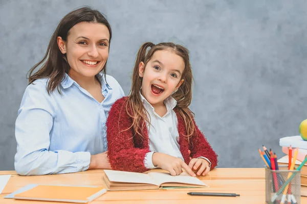 Lächelnde Mutter und Tochter beim Lesen eines Buches. Während dieser Zeit ist es angenehm, mit einem Lächeln in die Kamera zu schauen. — Stockfoto