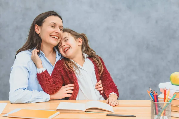 Χαμογελαστή μαμά και κόρη που διαβάζουν ένα βιβλίο. Κατά τη διάρκεια αυτού του χρόνου, είναι ευχάριστο να περνούν το χρόνο τους κοιτάζοντας την κάμερα με ένα χαμόγελο. — Φωτογραφία Αρχείου