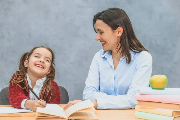 Anne gri bir arka plan üzerinde matematik ödevi ile kızı yardımcı olur. Bu esnada birbirlerine ve siren gülümsemeye bakıyorlar..