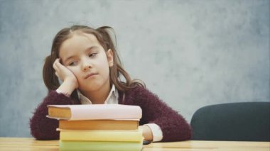 Küçük bir kız öğrenci masada bir sürü kitapla uyuyor. Birçok ev ödevi veya sınav küçük çocuklar için stresli. Ağır okul programı.