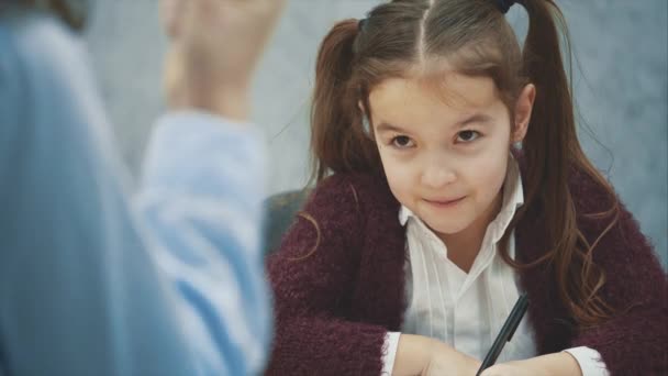 Une fille sur fond gris écrit ses devoirs. Pendant cette maman va se disputer et agiter son poing. Notion de relations . — Video