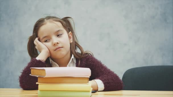 Mała uczennica śpi przy stole z wieloma książkami. Wiele prac domowych lub egzaminów są stresujące dla małych dzieci. Program dla szkół ciężkich. — Wideo stockowe