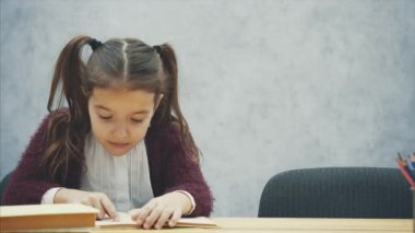 Anne kızı sohbet ederken kitap okuyor. Gri arka plan.
