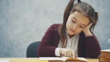 Çalışkan bir kız kitap okur. Annem yeşil bir elma getirdi. Gri bir arka plan üzerinde oturun.