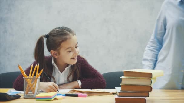 Mama hilft meiner Tochter bei den Hausaufgaben in der Küche. Mutter und Tochter beschäftigen sich mit dem Lesen. sie sind gut gelaunt und lächeln. — Stockvideo