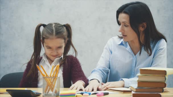 Schöne Schülerin, die am Tisch sitzt. Hausaufgaben mit der Mutter zu Hause. — Stockvideo