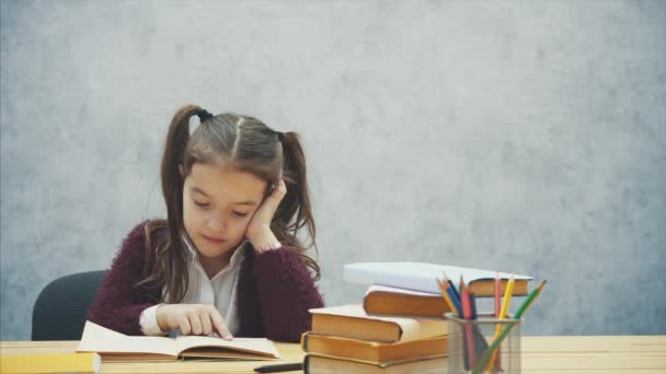 Een ijverige dochter leest een boek. Moeder bracht een groene appel. Zitten op een grijze achtergrond. — Stockvideo
