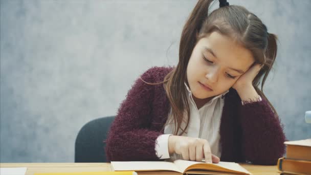 Een ijverige dochter leest een boek. Moeder bracht een groene appel. Zitten op een grijze achtergrond. — Stockvideo