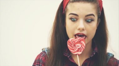 Pretty pinup kız yalama kırmızı kalp şeklinde lolly-pop, memnun yüz ifadesi.
