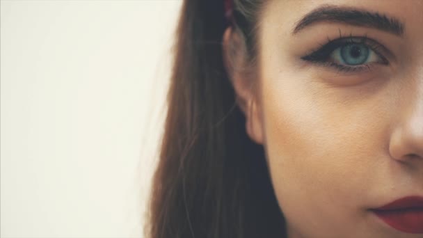 Cara de mitad de lado recortada de la joven chica encantadora mirando hacia abajo, luego a la cámara, sonriendo. Grandes ojos azules . — Vídeo de stock