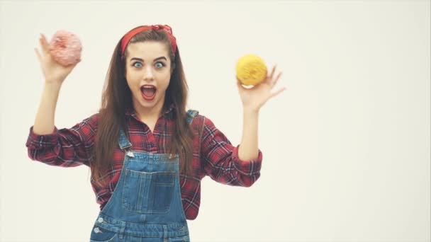 Мила дівчина-піппі ховає очі за великими рожевими і жовтими пончиками, позує, посміхається . — стокове відео