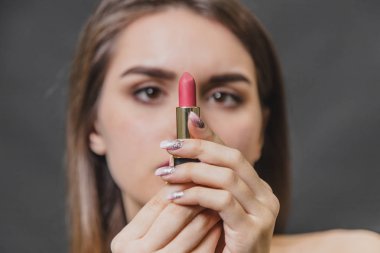 Güzel genç kız siyah bir arka plan üzerinde duruyor. Bu büküm sırasında, kırmızı ruj yakın.