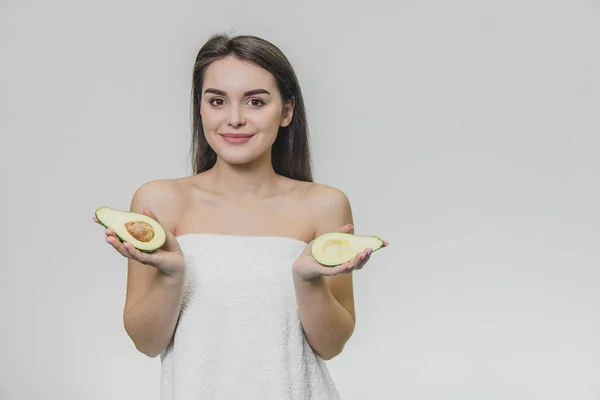 Retrato de mujer joven con piel limpia y pura sosteniendo aguacate en las manos . —  Fotos de Stock