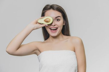 Yarım avokado ile beyaz havlu genç güzel kız. Gülümsüyor..