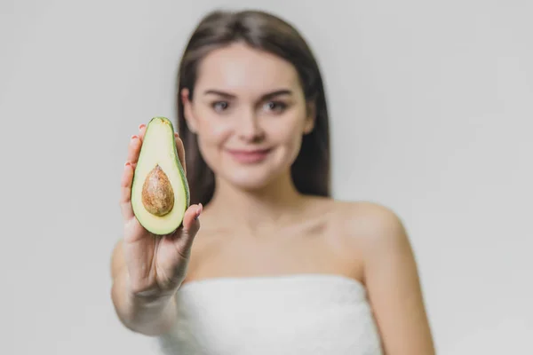 Close up focus portrait with half avocado and cute girl in white towel. — Stock Photo, Image