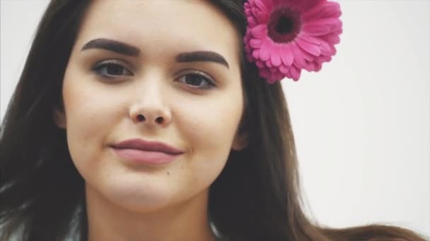 Jonge aantrekkelijke spa model vrouw met roze bloem, geïsoleerd op witte achtergrond. Mooie vrouw model van gezicht met schone frisse huid, geïsoleerd. — Stockvideo