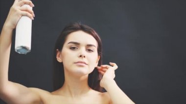 Çekici kadın siyah arka plan üzerinde izole saç spreyi püskürtme.