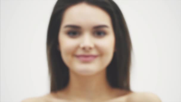 Young pretty girl standing on a white background. During this he raised the blurred flower with his hands in the position of the castle. — Stock Video