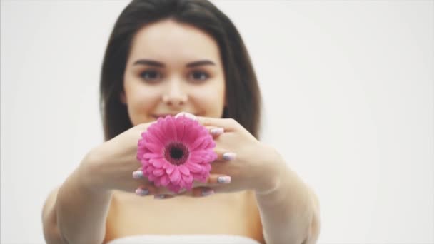 Junges hübsches Mädchen, das auf weißem Hintergrund steht. Dabei hob er die verschwommene Blume mit den Händen in die Position des Schlosses. das Mädchen hat eine ziemlich saubere Haut. — Stockvideo