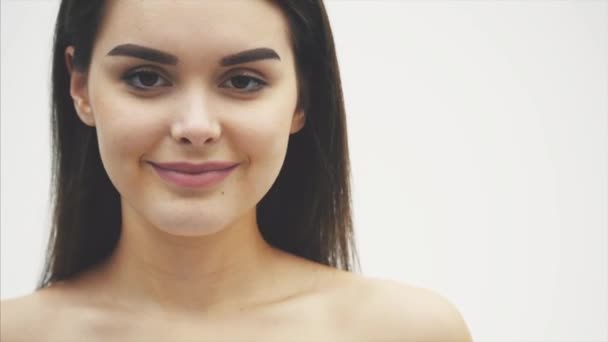 Close-up shot of a smiling girl with beautiful eyed without a make-up on a white background. The model demonstrates the benefits of avocado skin. — Stock Video