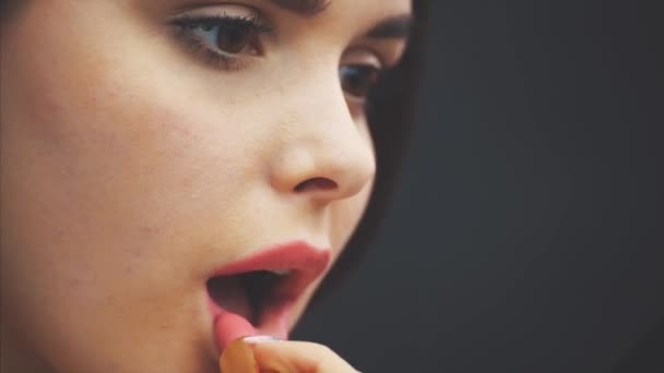 Concepto de belleza, cabeza y hombros de mujer joven mirando a la cámara y pintando labios con lápiz labial rosa. Retrato de primer plano de modelo con labios de rosa, estudio con fondo negro . — Vídeos de Stock
