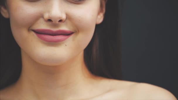 Beauty brunette woman with perfect makeup. A nice professional makeup holiday. Red lips, perfect eyebrows. The beauty of a girl face is isolated on a dark background. — Stock Video
