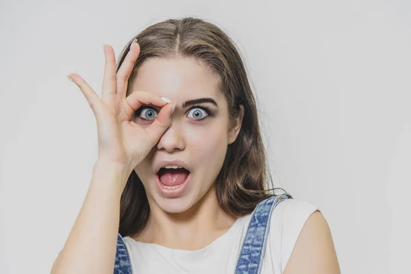 Ritratto ravvicinato di felice, bella, fiducioso, elegante. Ragazza sorridente in camicia bianca mostrando segno OK in piedi su sfondo grigio . — Foto Stock