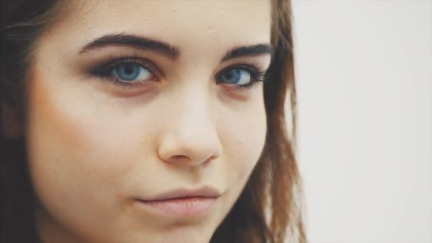 Young beautiful girl standing in profile the looking at the camera with curious face expression, raising her eyebrow, winking at the camera and smiling. — Stock Video