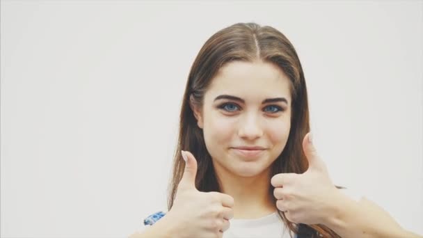 Bella ragazza guardando la fotocamera e indicando qualcosa dietro di lei, poi dando pollice in su. Capelli ondulati donna, espressioni facciali espressive — Video Stock