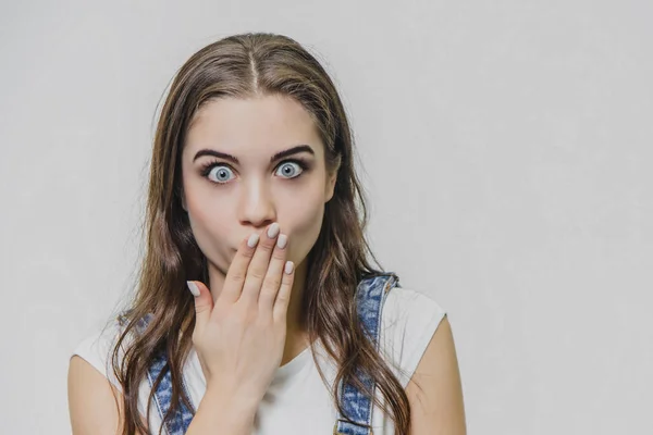 Ritratto orizzontale di bella donna con espressione gonfia, trova soluzione, indossa maglietta casual con tuta in denim, isolata su sfondo bianco. Adorabile bella studentessa pensa indoor — Foto Stock