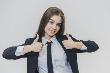 Kadın el hareketleri başparmak kadar. Kız onu sevimli yüzüne kadar bir yükseltilmiş başparmak ipuçları ile sağ ve sol ellerini tahsis eder. İş kızı geniş gülümsüyor ve olumlu duygular paylaşıyor.