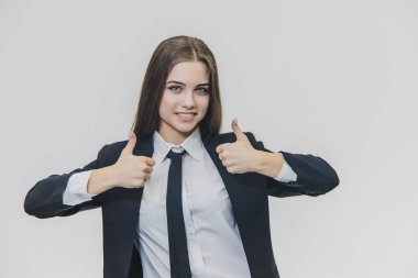 Kadın el hareketleri başparmak kadar. Kız sağ ve sol ellerini başparmaklarla birikiyor. İş kızı geniş gülümsüyor ve olumlu duygular paylaşıyor.