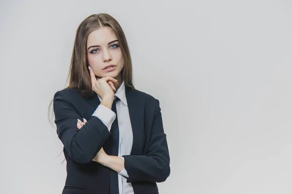 Jonge mooie zakenvrouw denkt met haar hand op kin. — Stockfoto