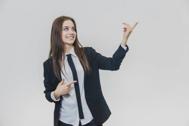 Gülümseyen düşünceli kahverengi saçlı iş kadını işaret ediyor ve yukarı bakıyor.