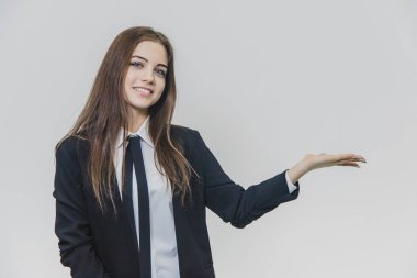 Gülümseyen, düşünceli kahverengi saçlı iş kadını bir şey sunuyor ve memnuniyeti ve samimi bir gülümseme ile kameraya bakıyor.