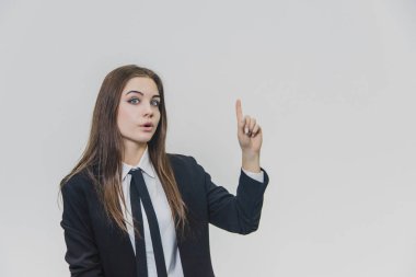 Genç güzel iş kadını bir eğlence, şaşkınlık ve göz kamaştırıcı yüz ifadesi ile parmağını işaret ediyor.