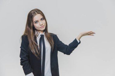 Ciddi düşünceli ve ince gülümsedi, kahverengi saçlı iş kadını beyaz arka plan üzerinde bir şey sunarken düşünüyor.