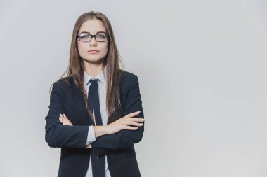 Siyah gözlüklü sevimli kendine güvenen iş kadını beyaz arka planda duruyor. Çekici kadın, profesyonel model izole edilir. Biraz gülümsüyor, bakımlı ellerini geçiyor.